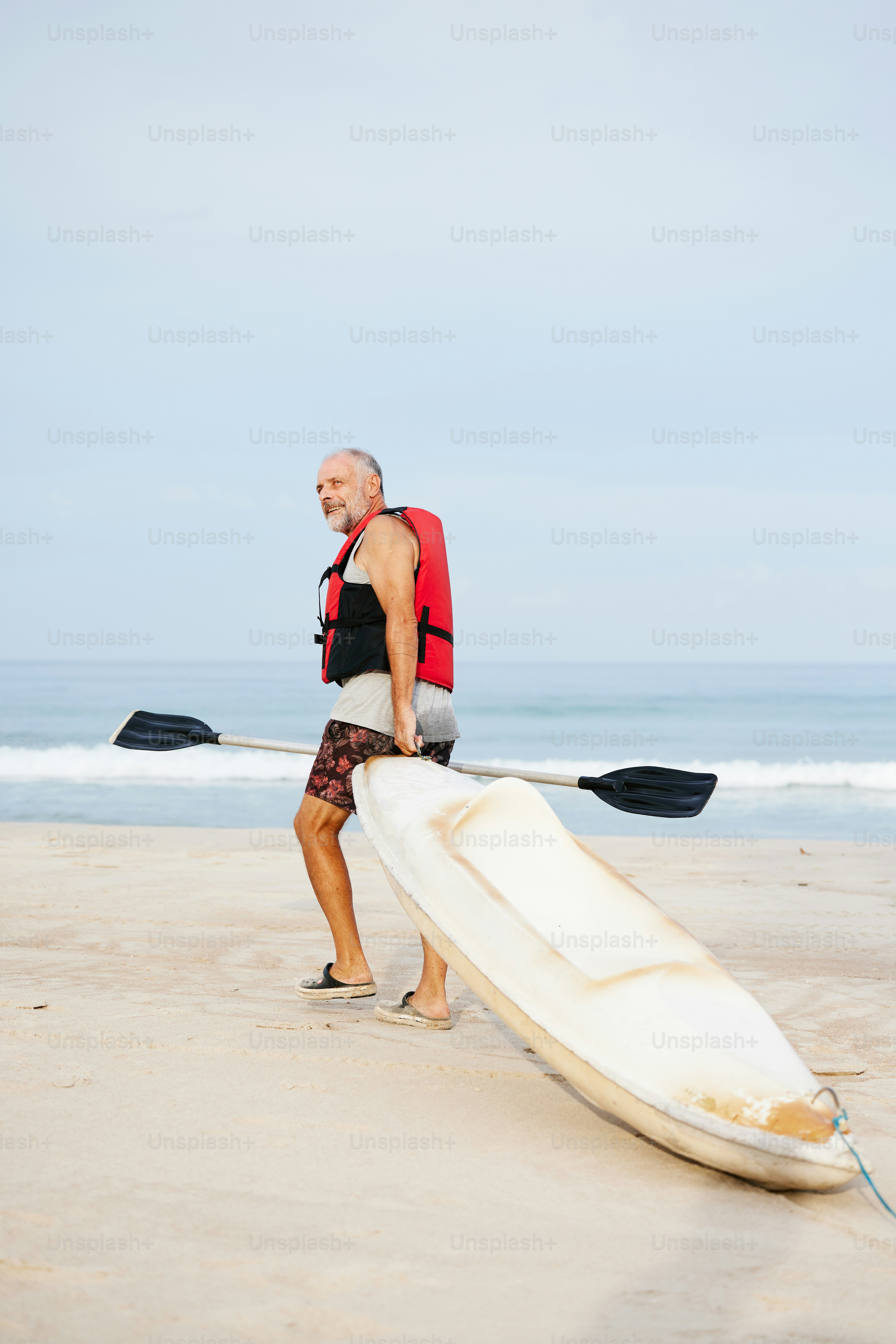 a man walking on the beach with a kayak