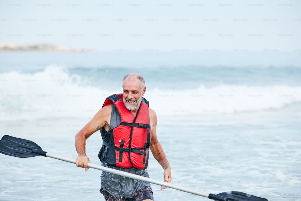 Un uomo in un giubbotto di salvataggio che pagaia un kayak nell'oceano