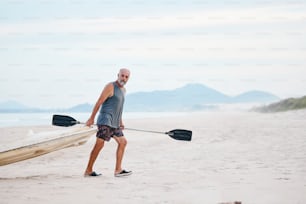 Un uomo che trasporta una canoa sulla spiaggia