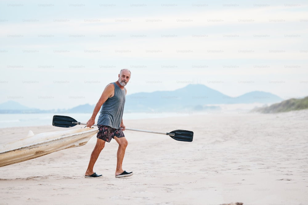 a man carrying a canoe on the beach