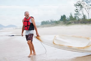 Un hombre sosteniendo una tabla de surf en la playa