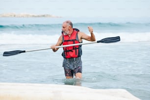 Ein Mann in einer Schwimmweste, der mit einem Kanu im Meer paddelt