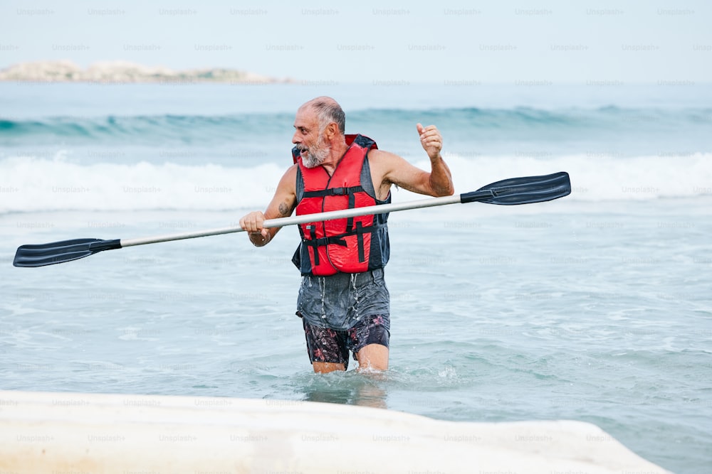 Un hombre con un chaleco salvavidas remando en una canoa en el océano