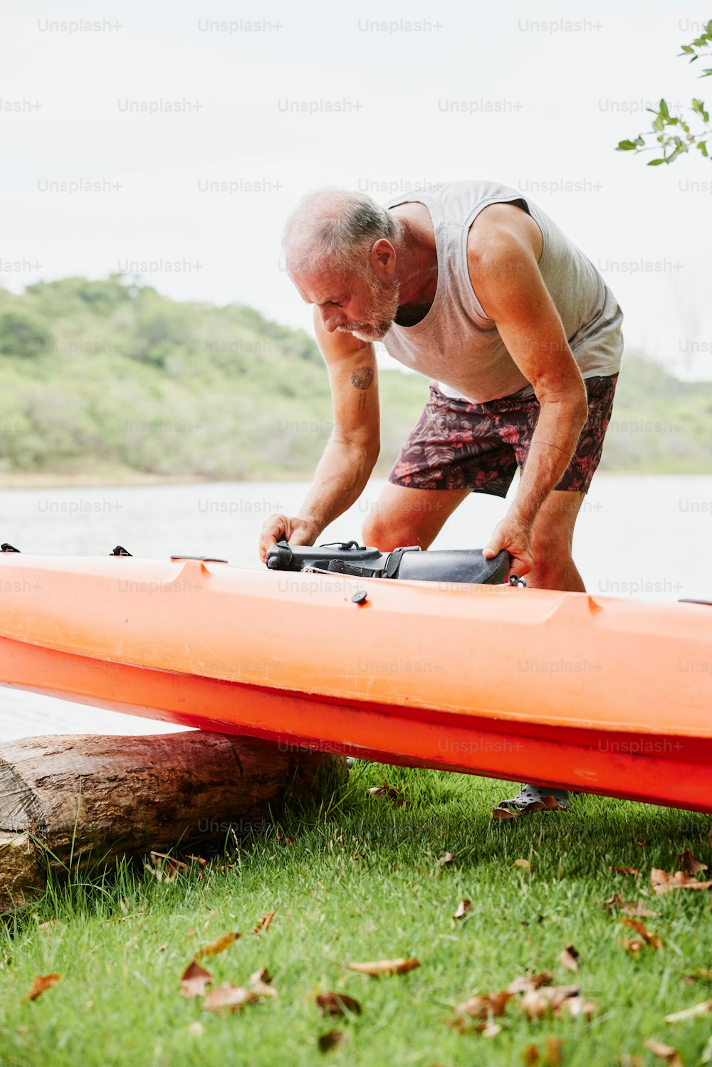 a man is bending over a kayak on the grass