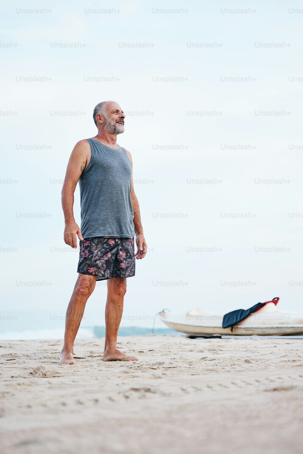 Un uomo in piedi su una spiaggia accanto a una barca