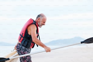 Ein Mann, der ein Surfbrett am Strand trägt