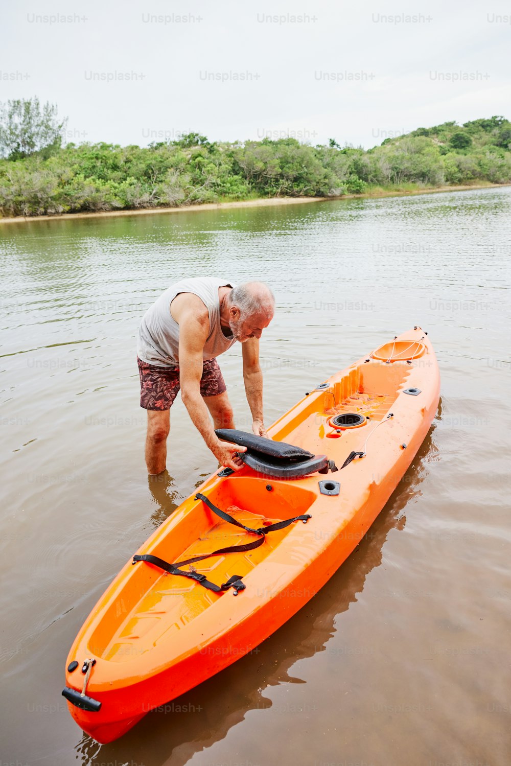 a man standing in the water next to an orange kayak