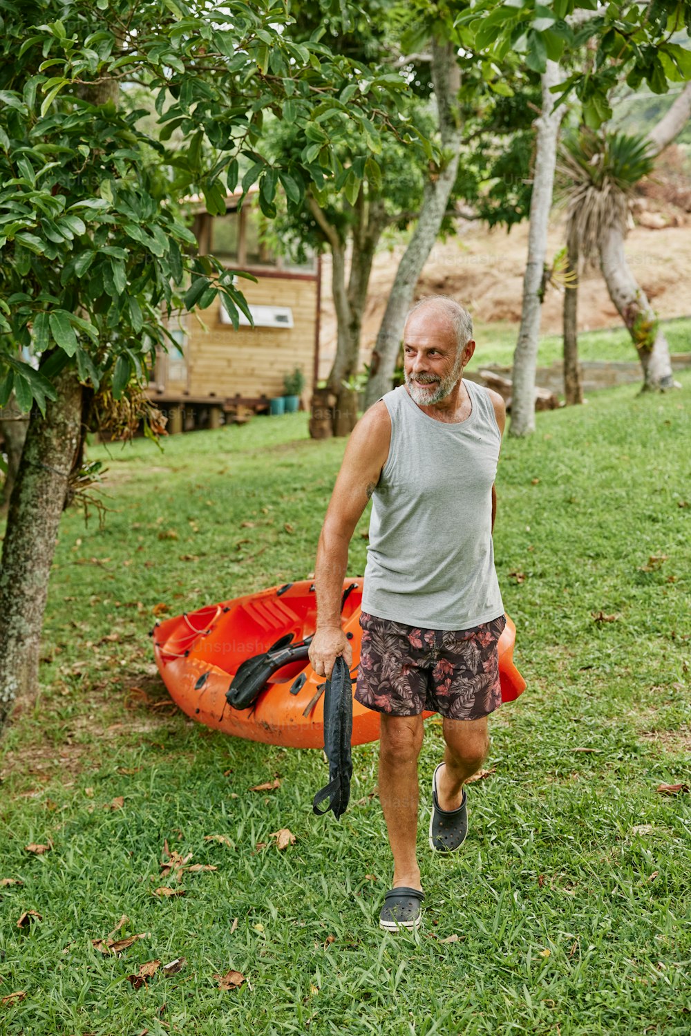 a man walking in the grass with a kayak behind him