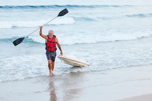 a man in a life jacket holding a paddle board and paddling a kayak