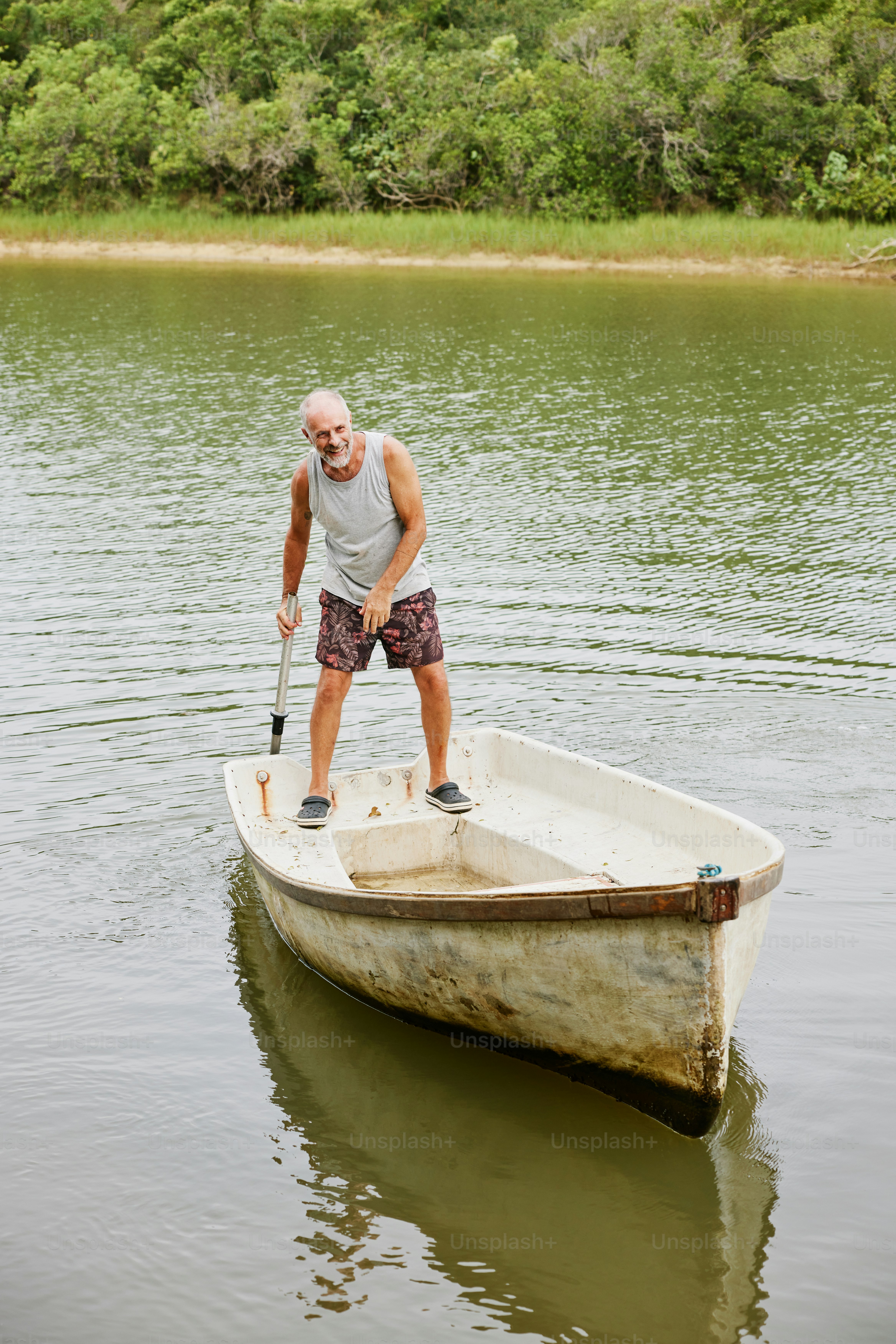 A man standing on a small boat in the water photo – Beach Image on Unsplash