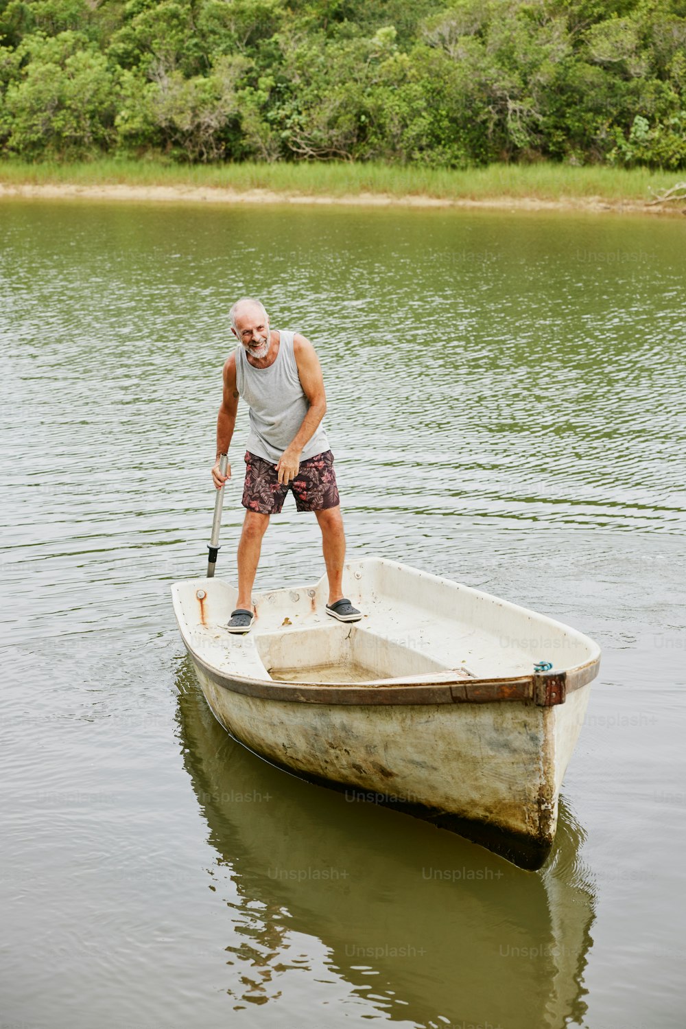 水中の小さなボートの上に立っている男