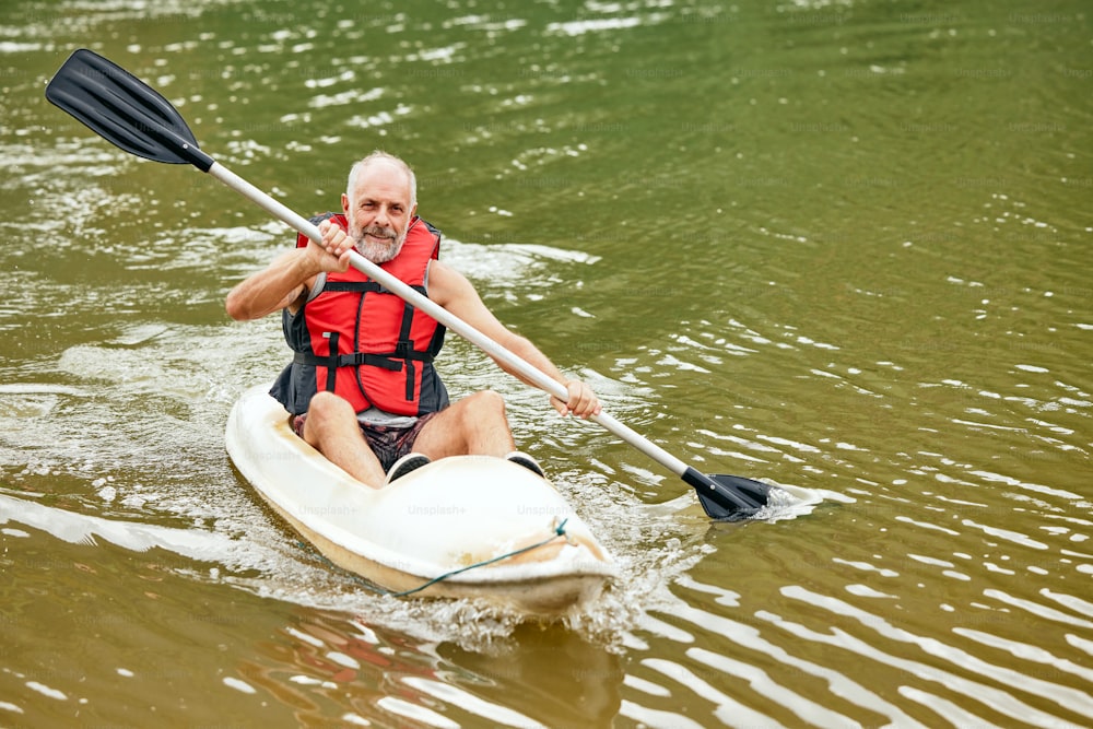 a man in a life jacket paddling a kayak