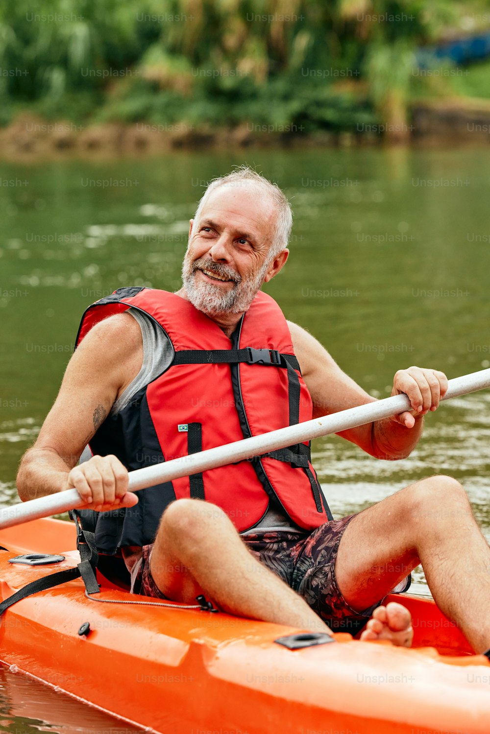 a man in a red life jacket paddling a kayak