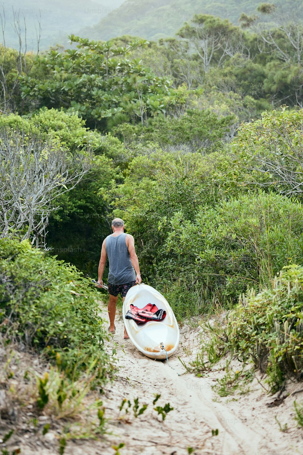 a man walking up a hill with a surfboard