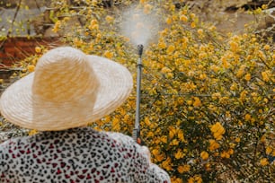 a woman wearing a white hat standing in front of a bush