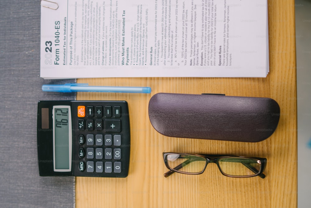 a pair of glasses, a calculator, a pen, and a book