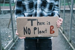 Una persona sosteniendo un letrero de cartón que dice que no hay planeta B