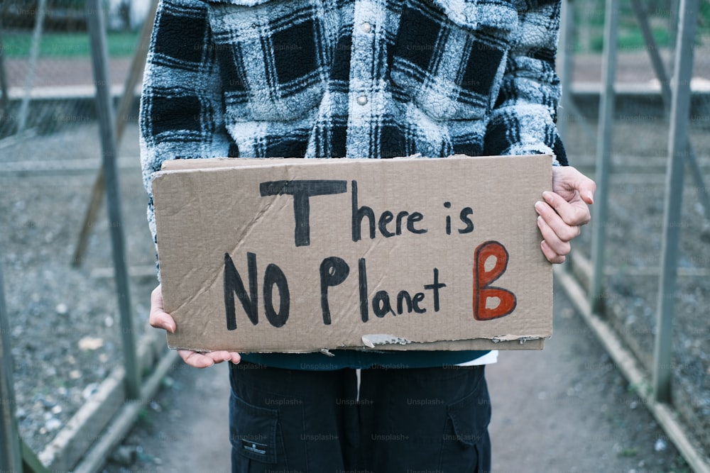 a person holding a cardboard sign that says there is no planet b