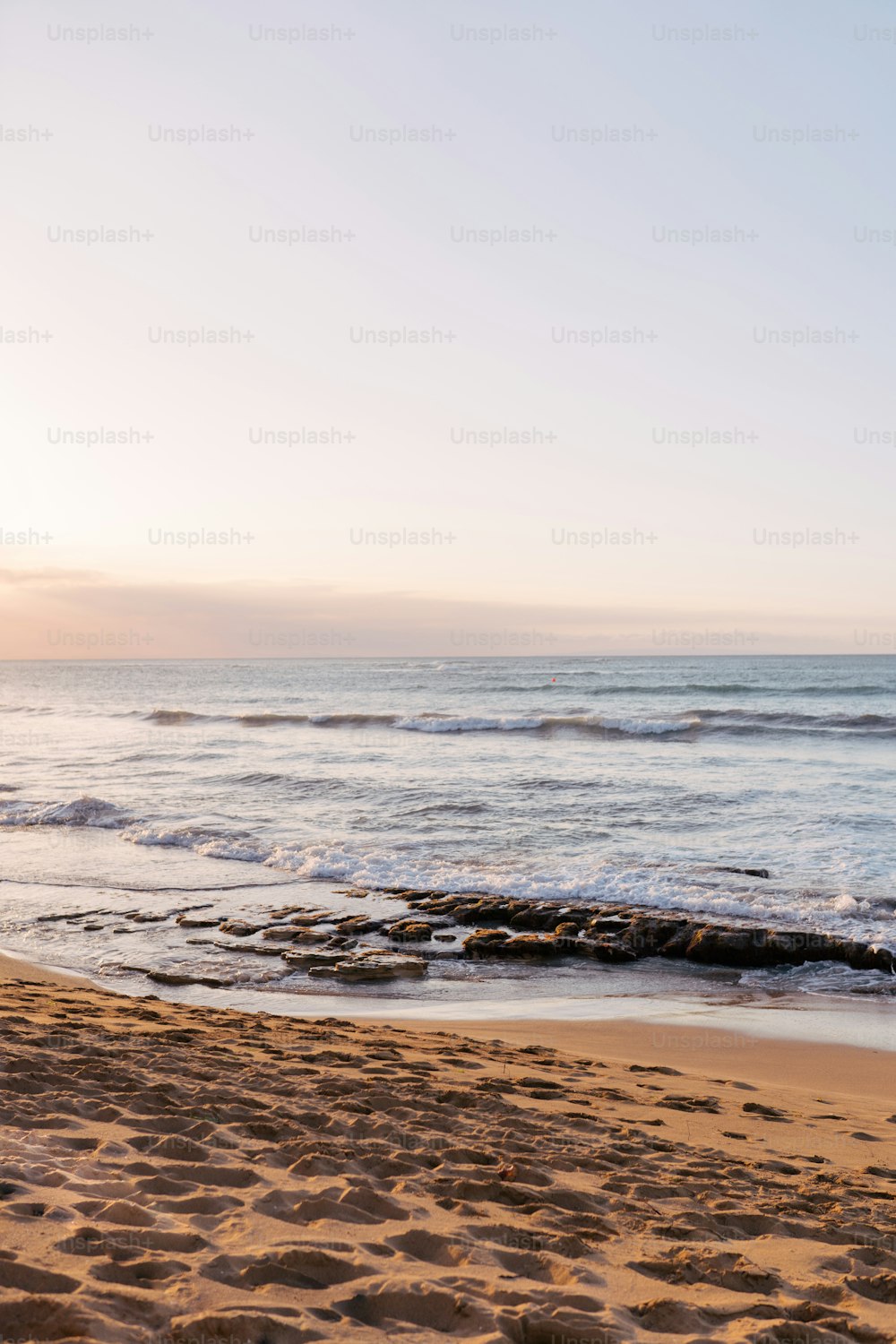 a person walking on a beach carrying a surfboard