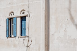 a white building with blue shutters and a clock