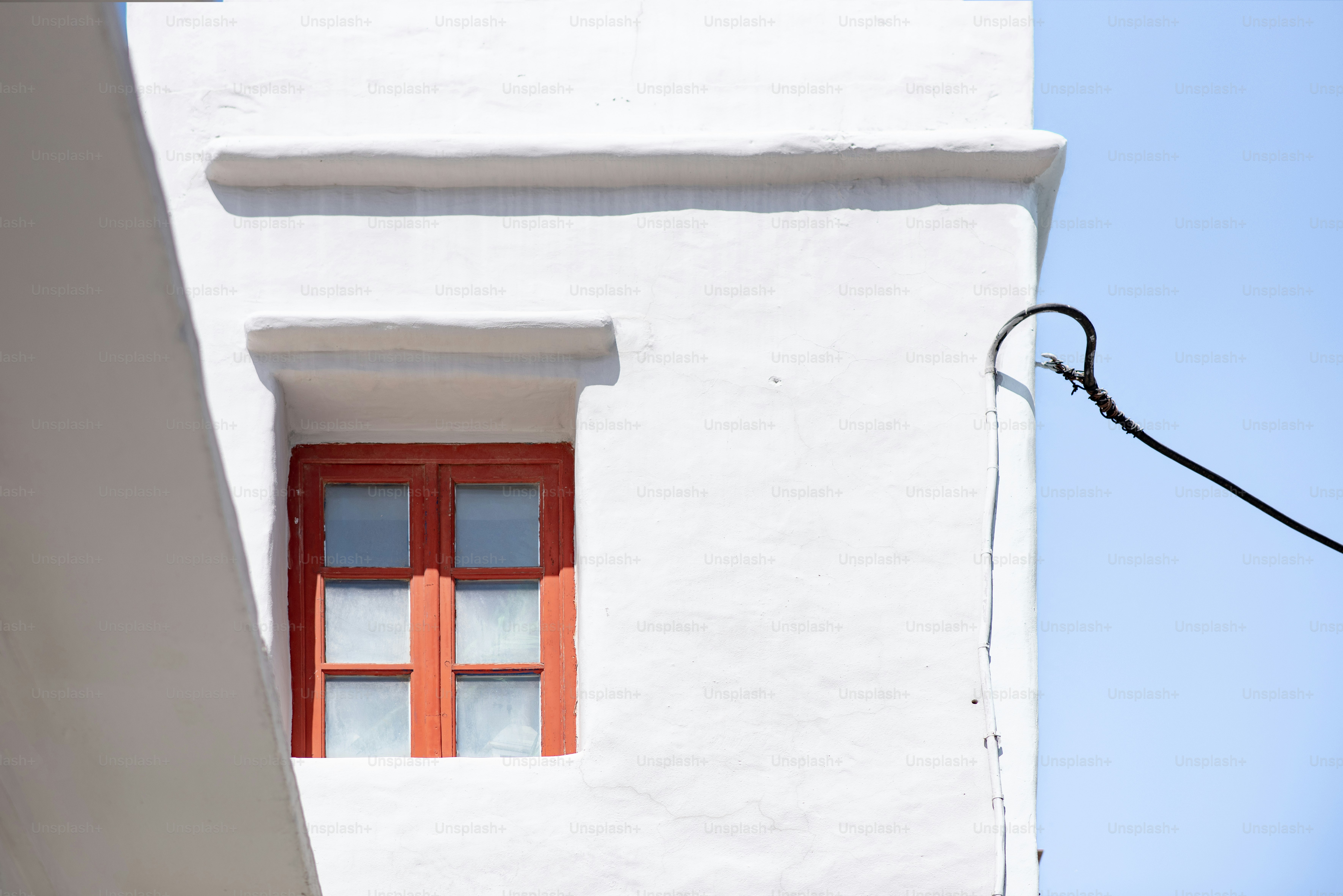 a white building with a red window and a street light