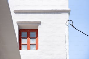 un bâtiment blanc avec une fenêtre rouge et un lampadaire
