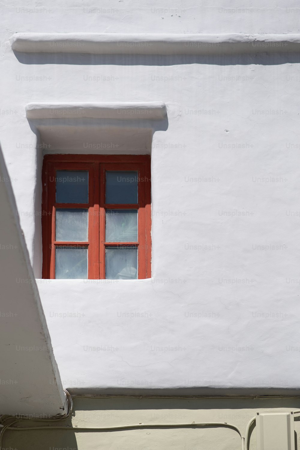 Ein weißes Gebäude mit einem roten Fenster und einer roten Tür