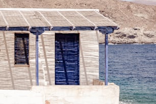 Un edificio blanco con persianas azules junto a un cuerpo de agua