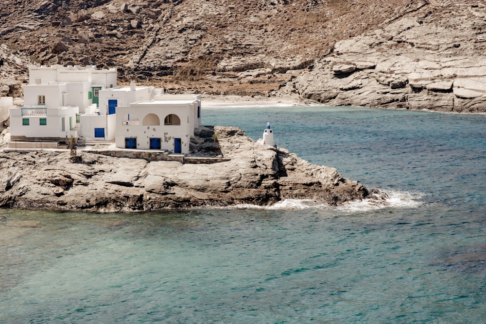 um edifício branco sentado no topo de um penhasco rochoso ao lado de um corpo de água