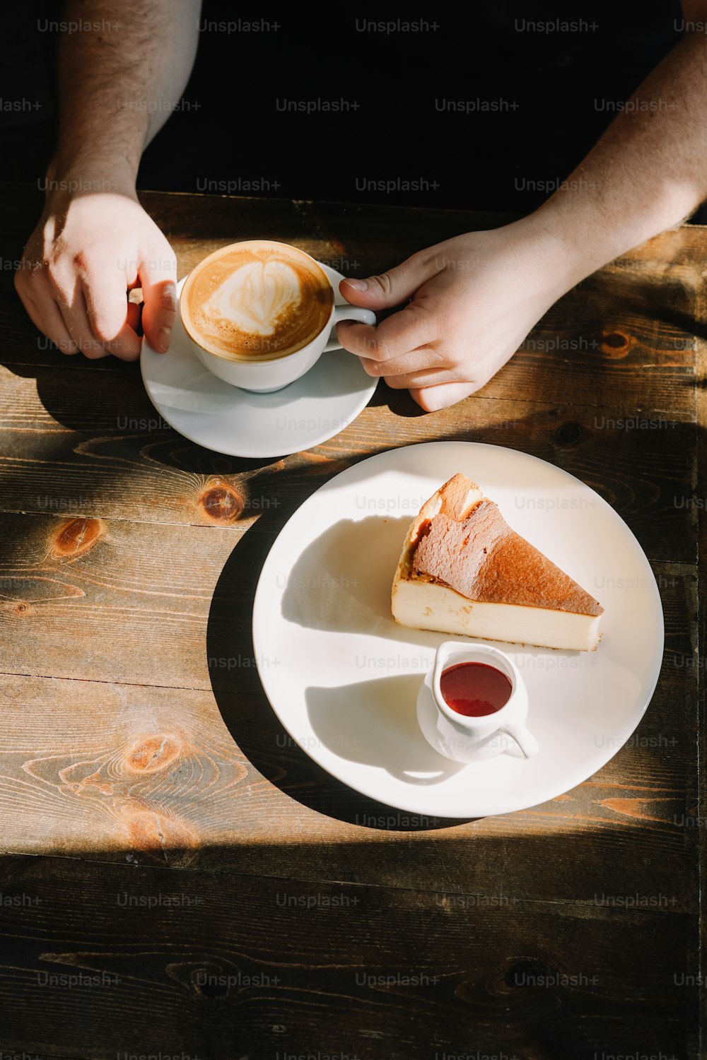 a person holding a cup of coffee and a slice of cake on a plate