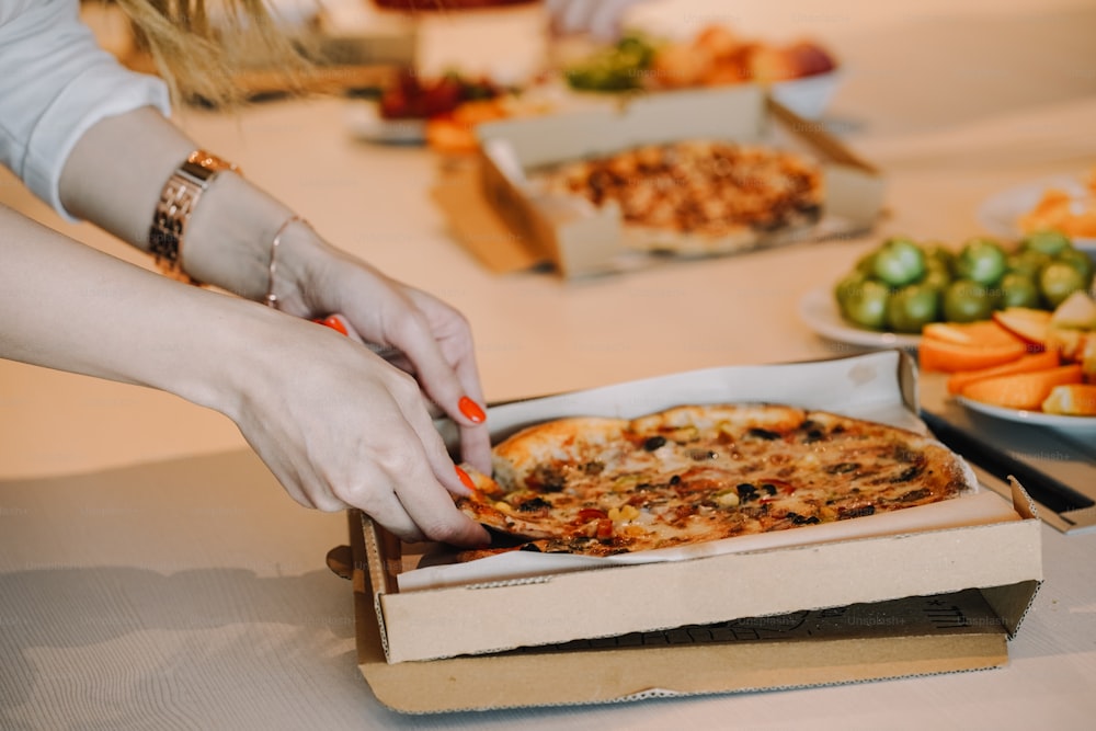 a person grabbing a slice of pizza out of a box