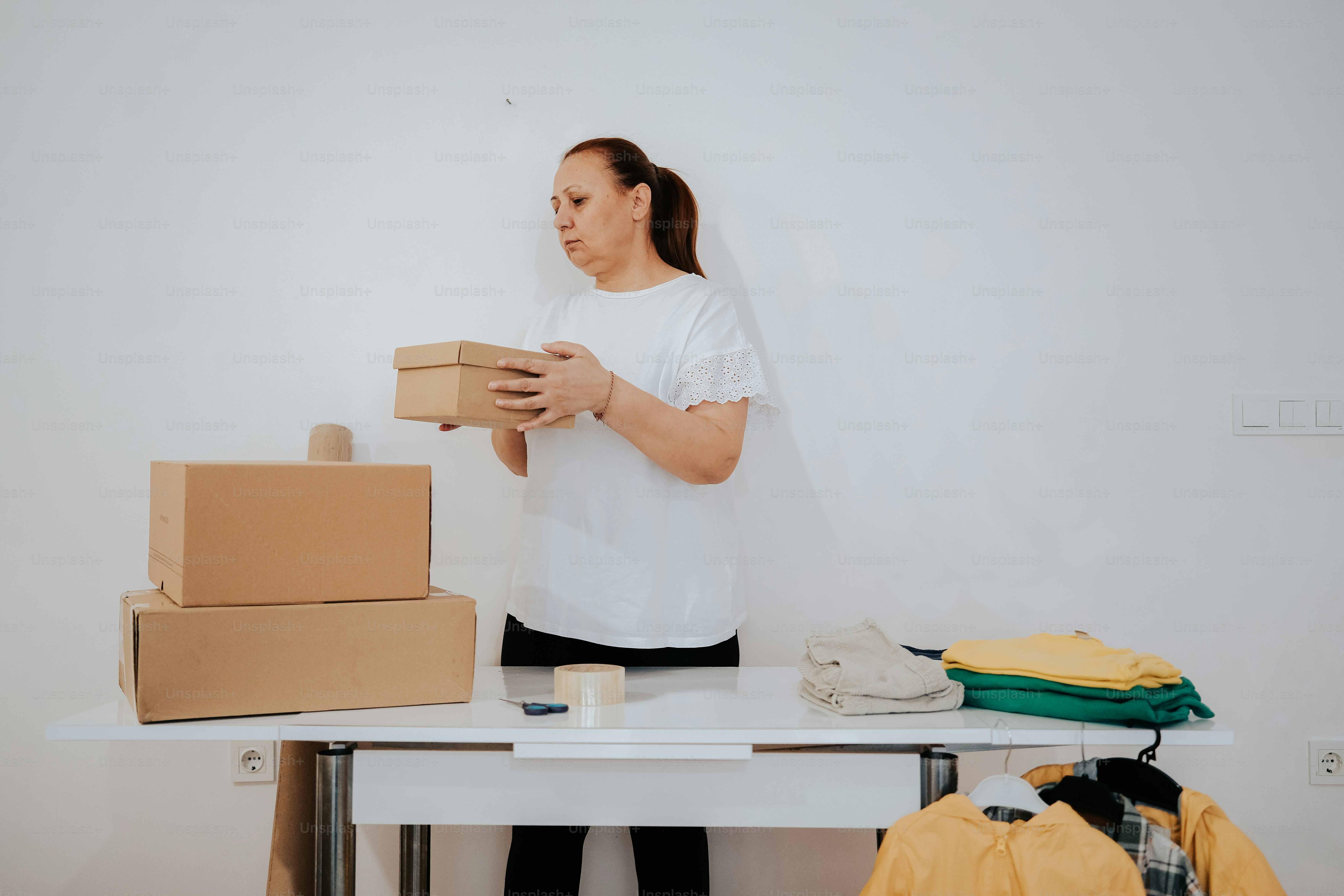 a woman standing next to a table holding a box