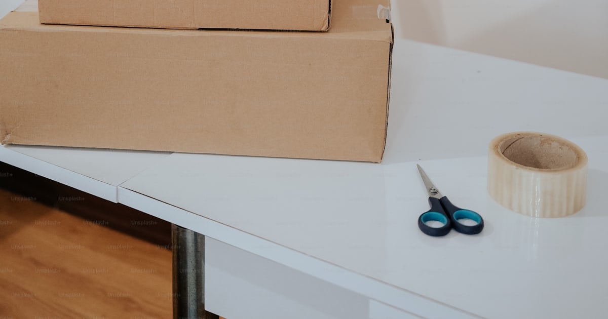 A stack of boxes sitting on top of a white table photo – Packing Image ...