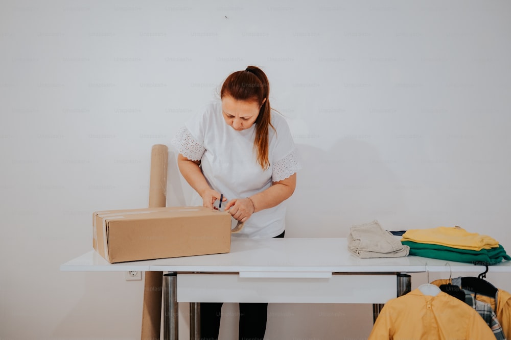 a woman standing at a table cutting a cardboard box