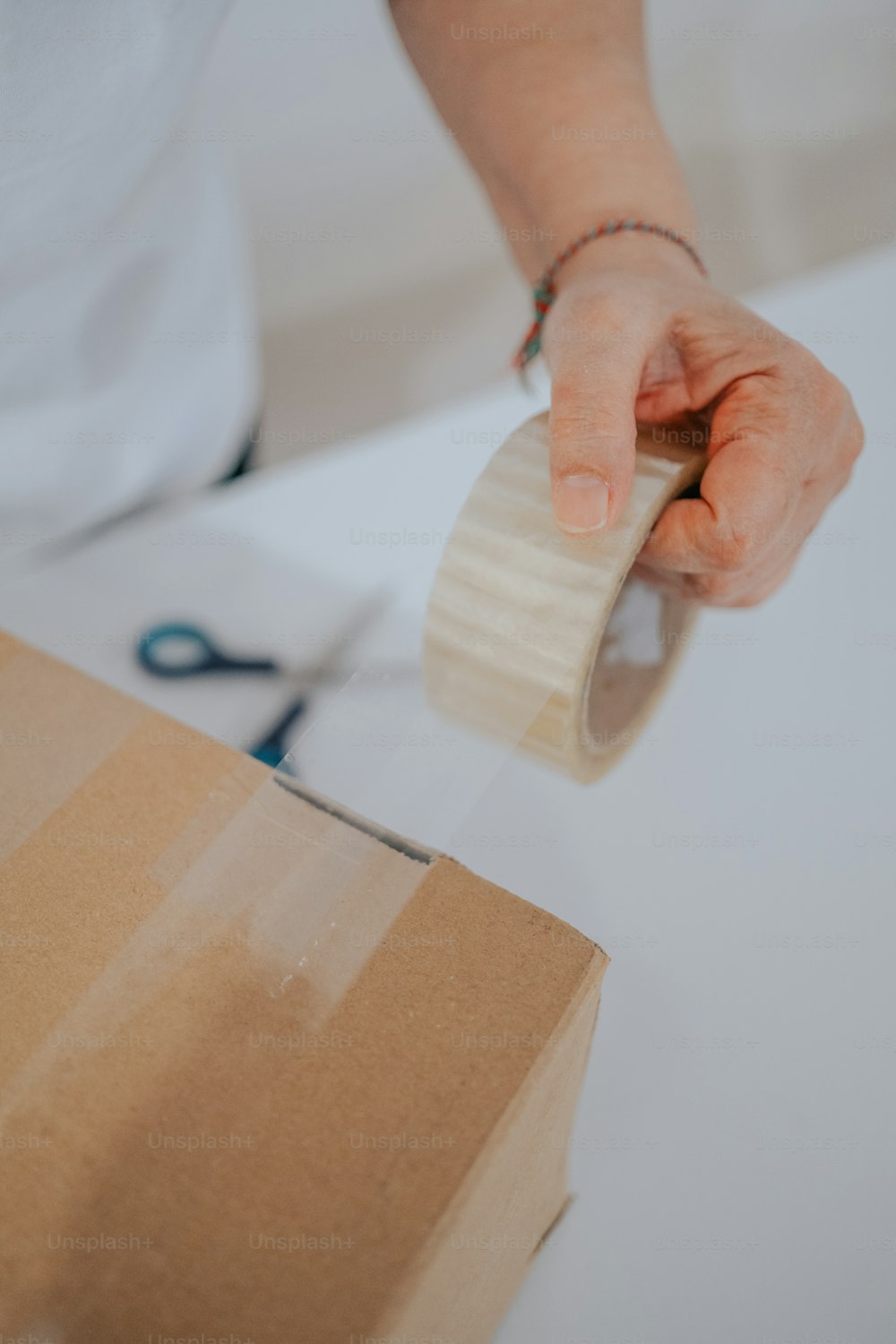 Una persona sosteniendo un rollo de cinta adhesiva sobre una caja