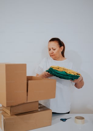 a woman holding a green cloth over a cardboard box