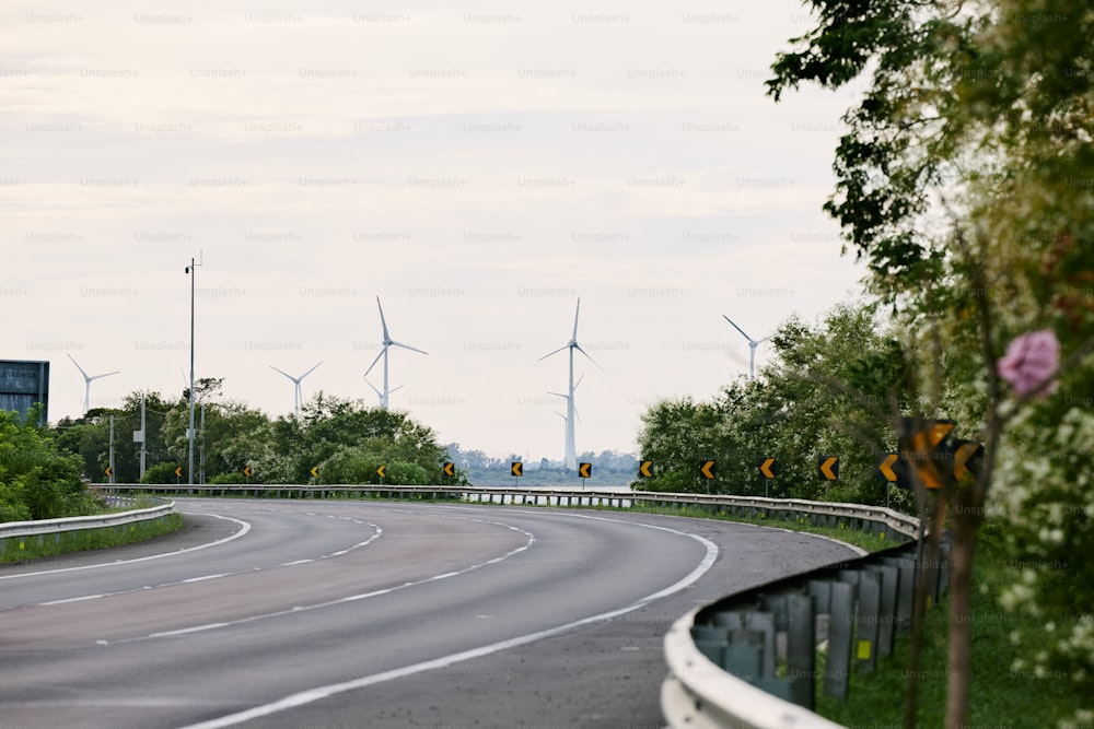 a winding road with wind turbines in the background