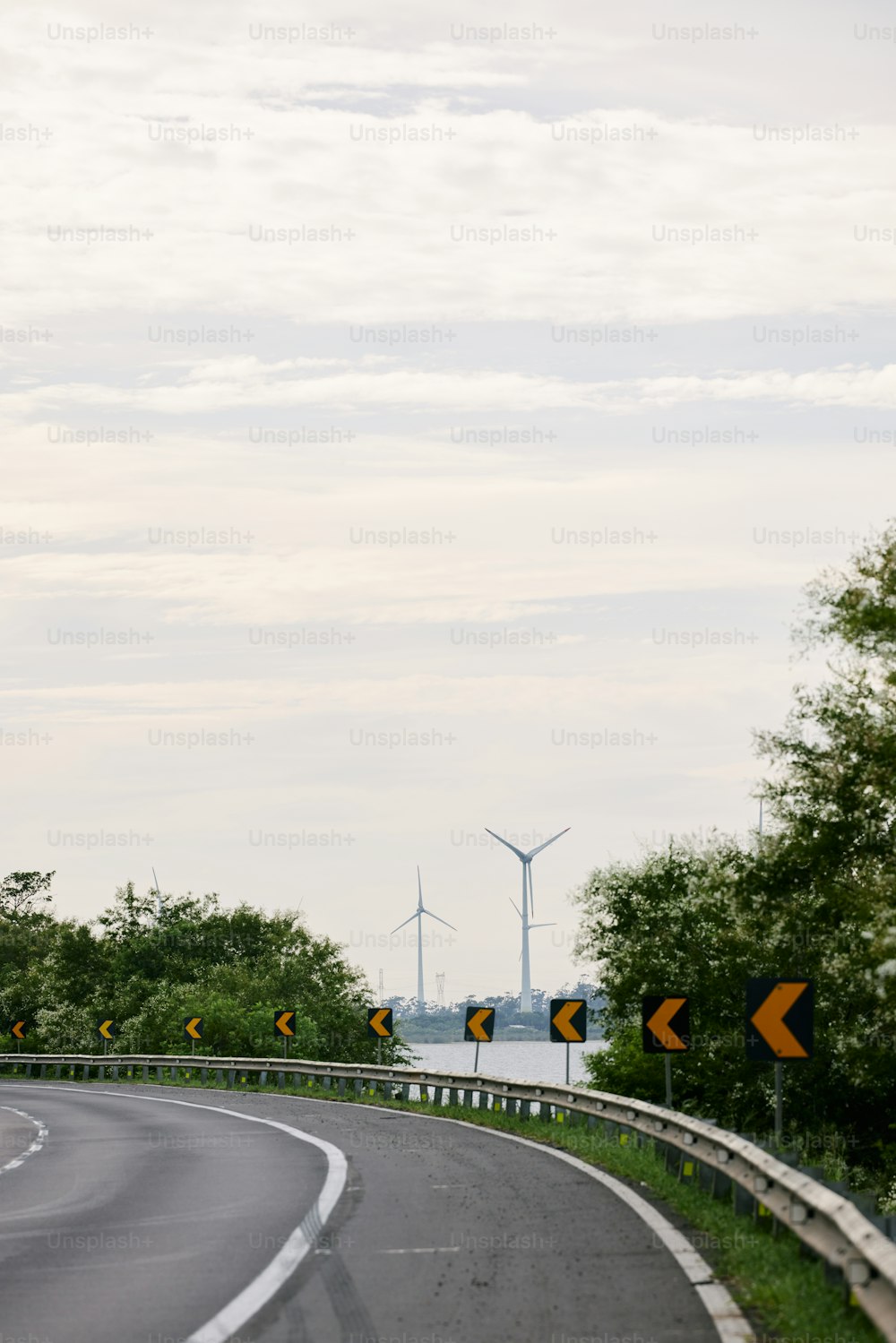 a winding road with a wind turbine in the background