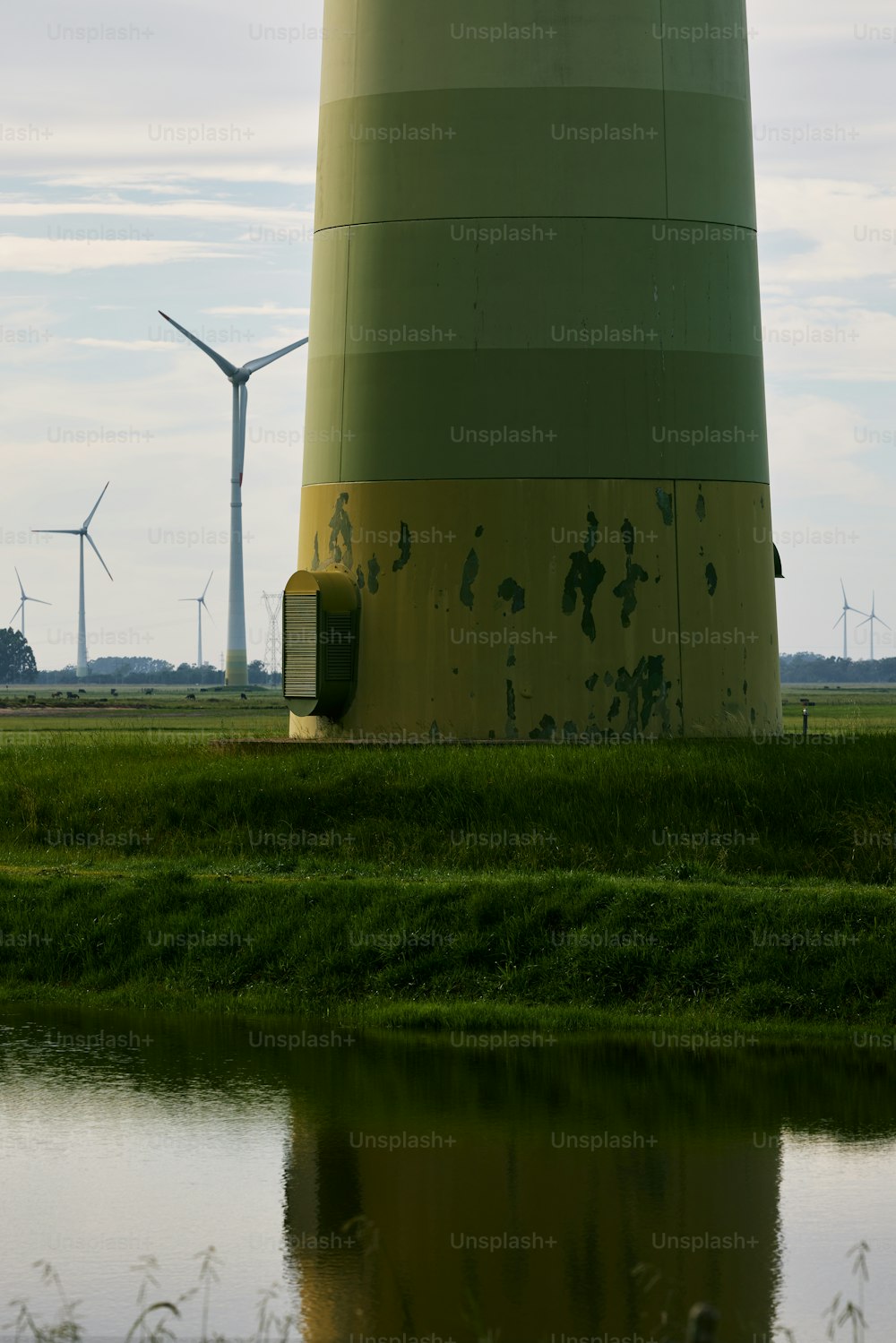 a large green and yellow tower next to a body of water