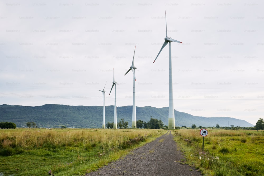 a dirt road in front of a row of wind turbines