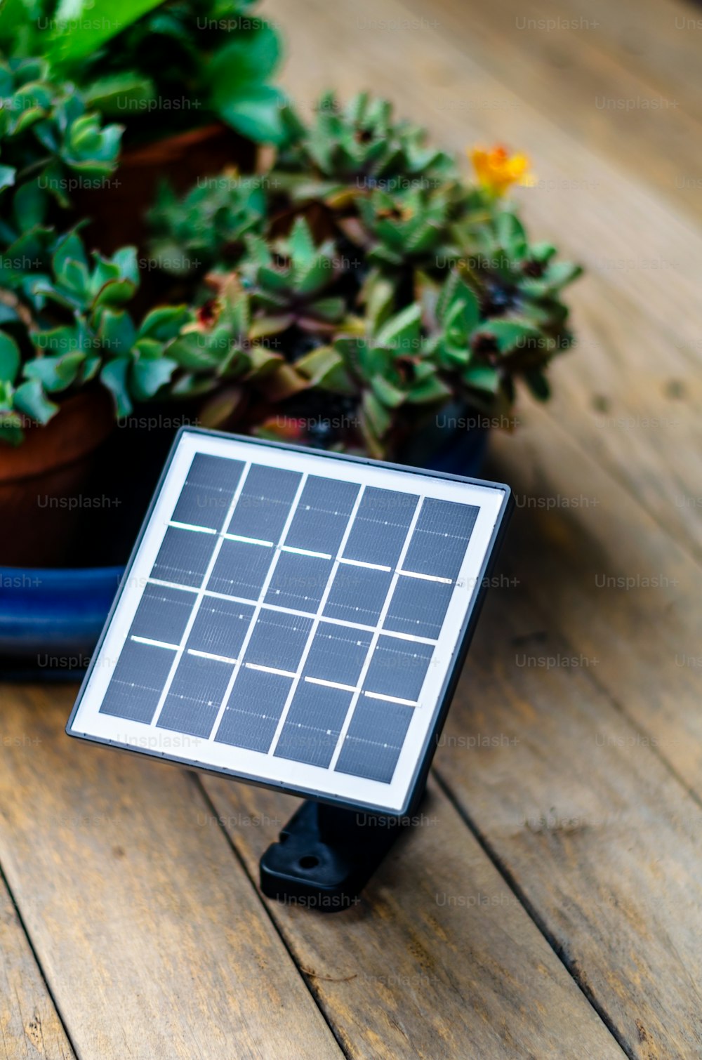 a solar panel sitting on top of a wooden table next to a potted plant