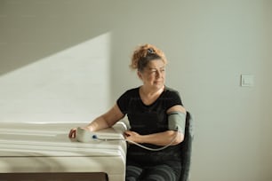 a woman sitting on a bed with an electric device in her hand