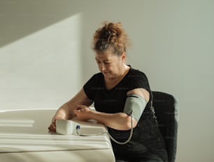 uma mulher com um molde em seu braço sentado em uma mesa