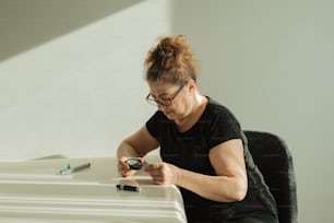 Eine Frau sitzt mit einem Handy an einem Schreibtisch