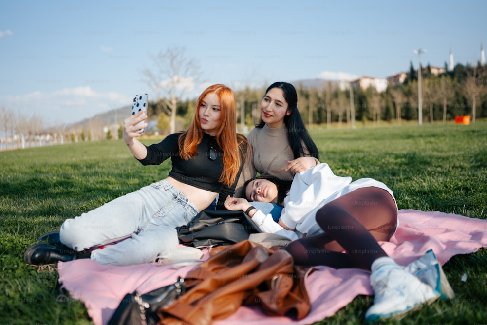 two women sitting on a blanket taking a picture of themselves