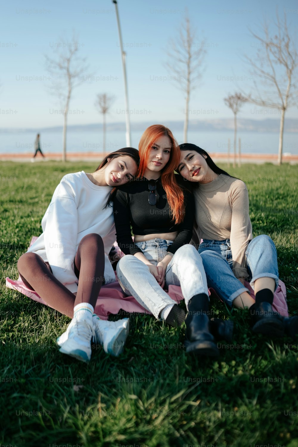 three girls are sitting on a blanket in the grass