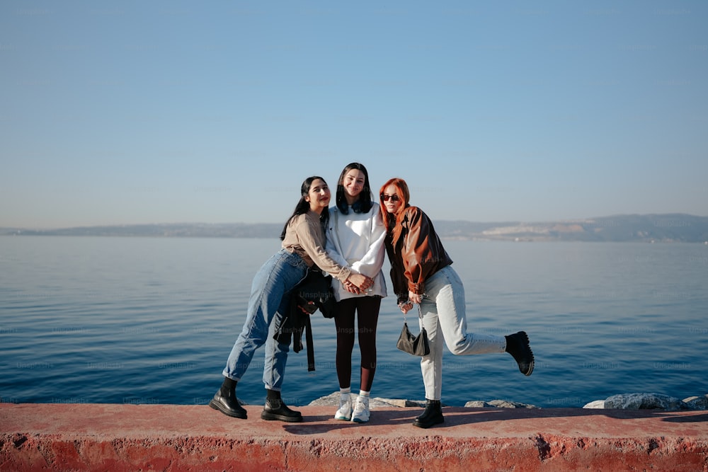 três meninas posando para uma foto à beira da água