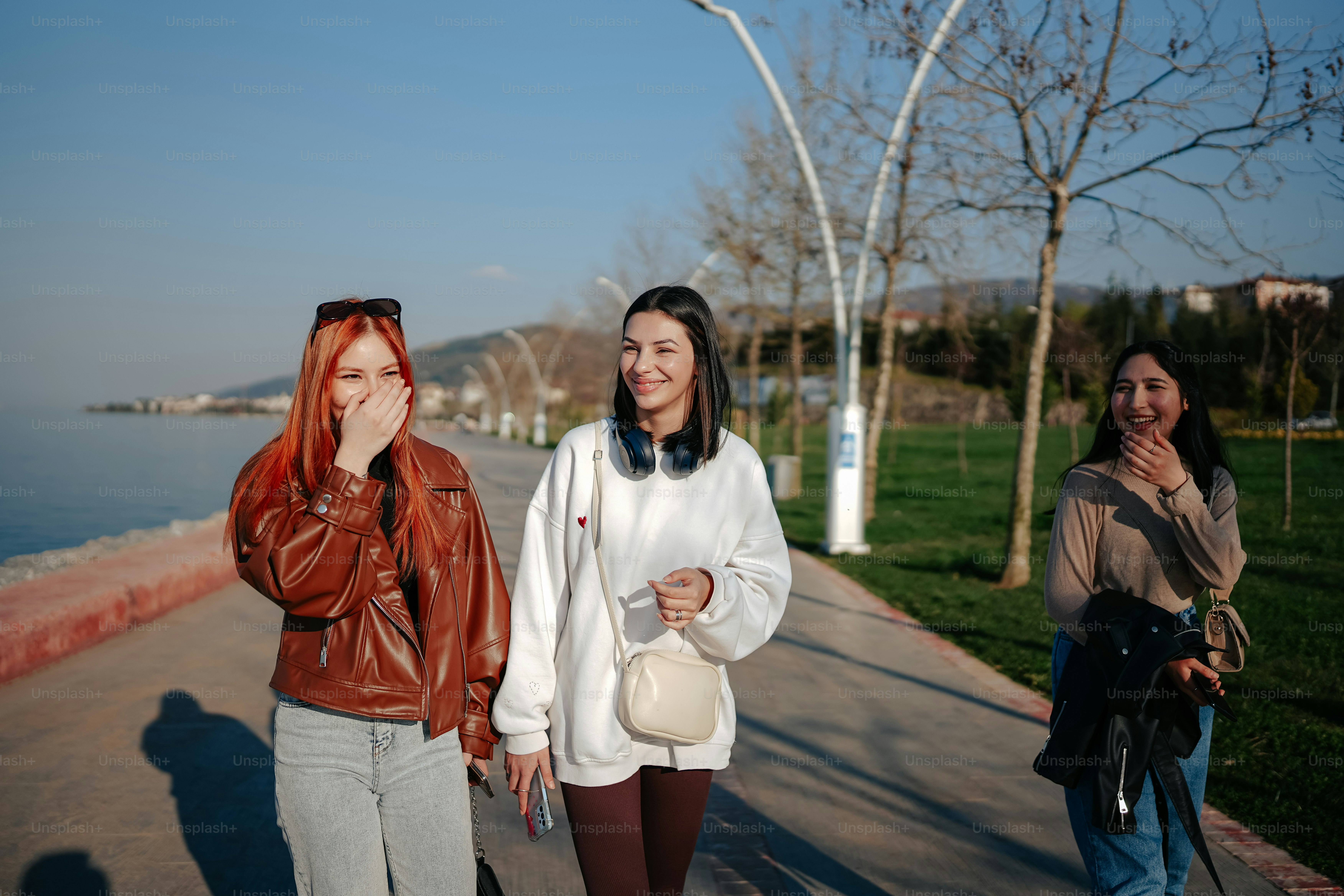 a group of women walking down a sidewalk next to the ocean