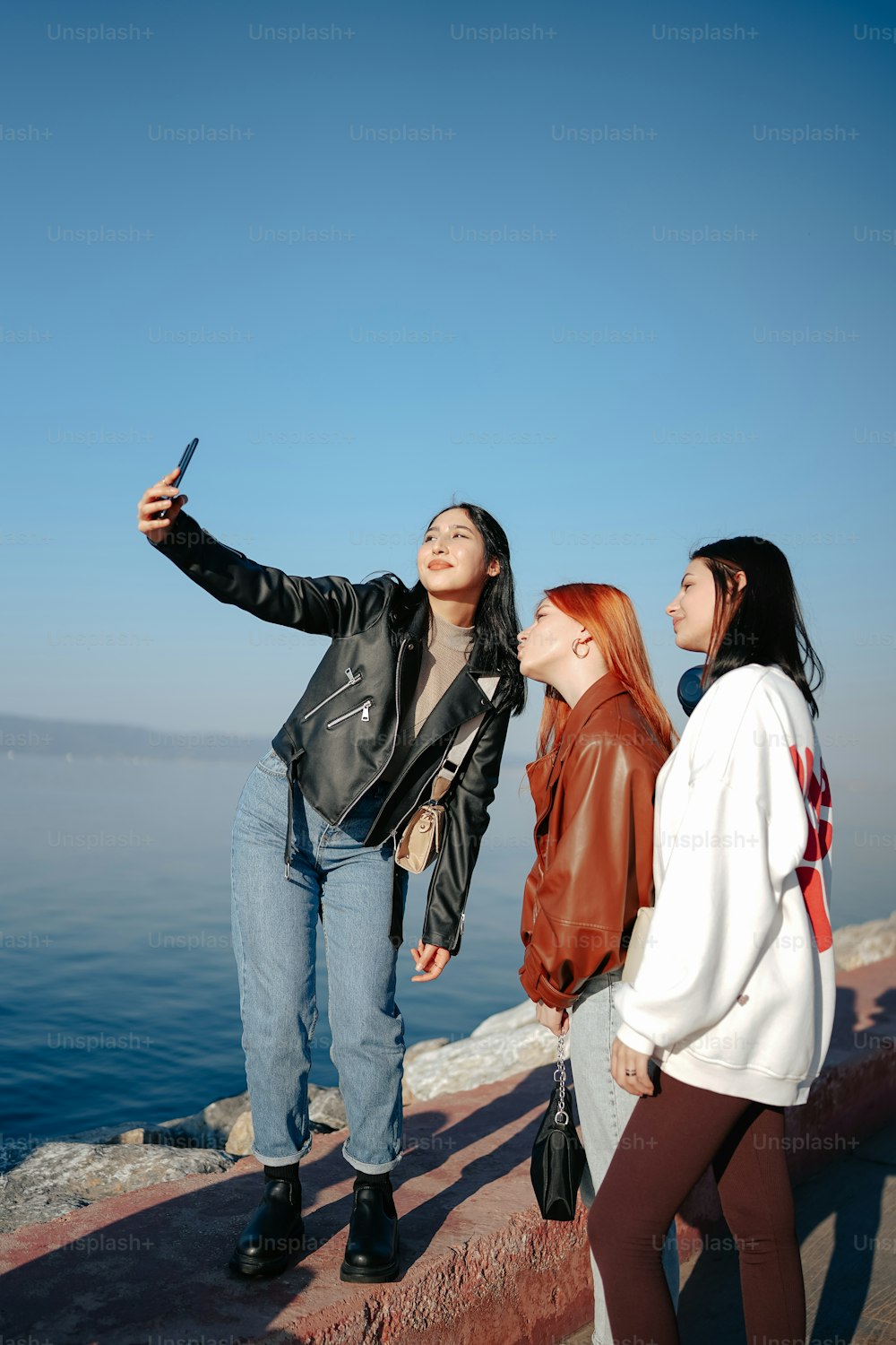 three women standing on a ledge looking up at the sky