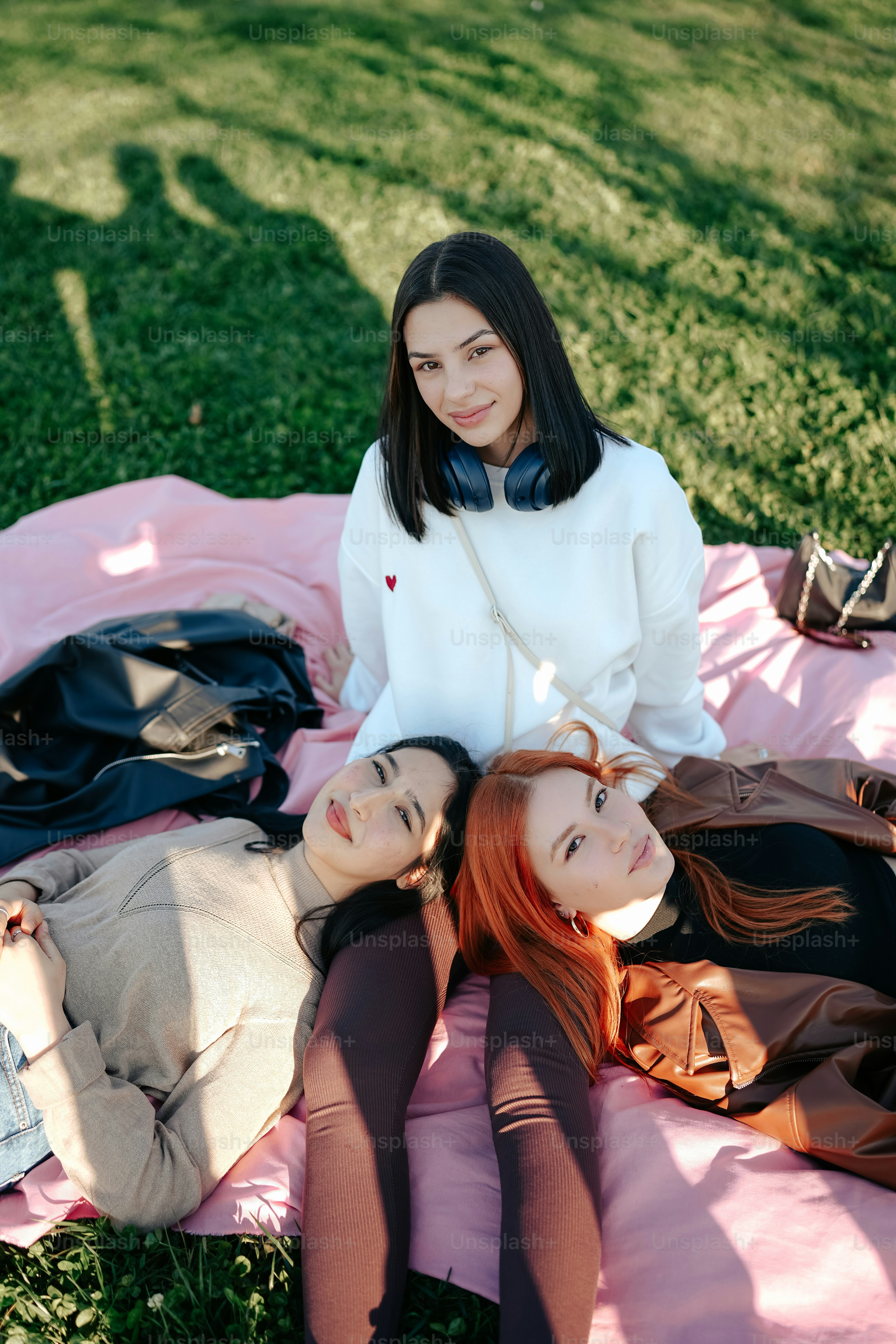 two women sitting on a blanket in the grass